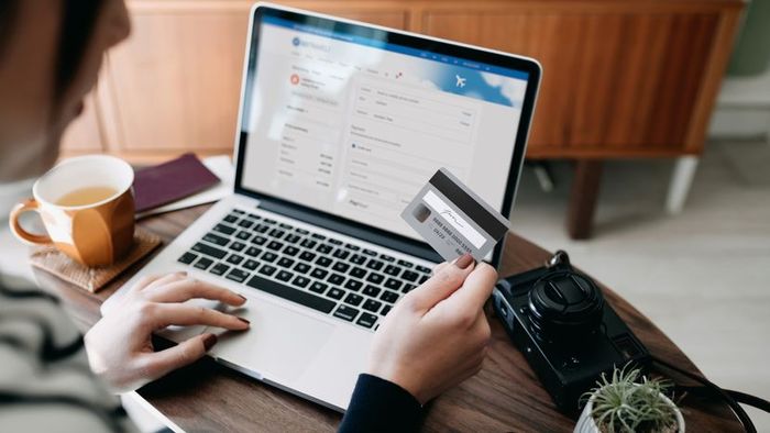 A woman making an online payment for airline tickets with her card.