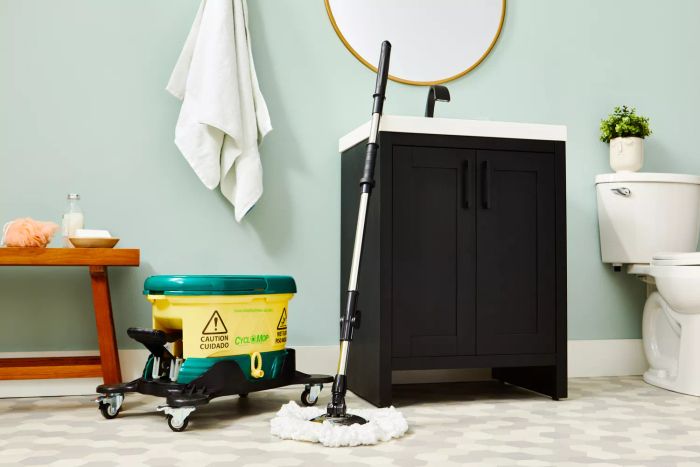 Bissell Commercial CycloMop Spin Mop placed on tile flooring, leaning against a bathroom sink