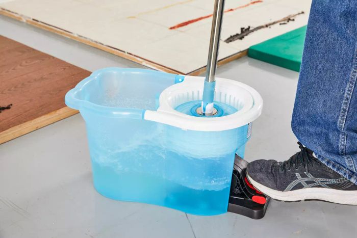 A foot presses down on the spin pedal of the Hurricane Spin Mop.