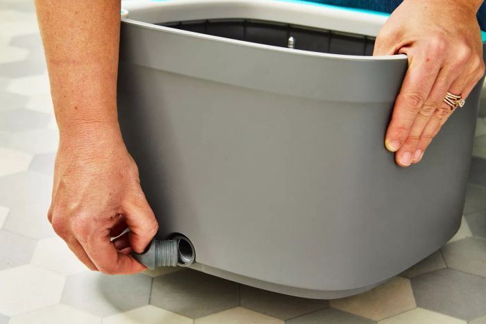 Person removing the cover from the drain of the True & Tidy TrueClean Spin Mop and Bucket System