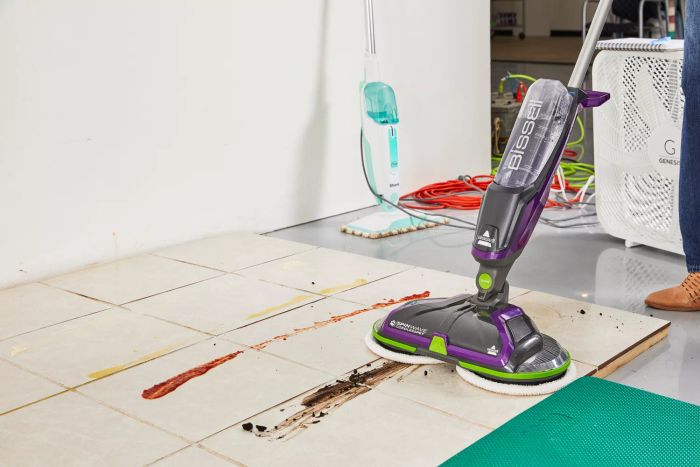 A person is cleaning tile flooring using the Bissell SpinWave Cordless PET Hard Floor Spin Mop.