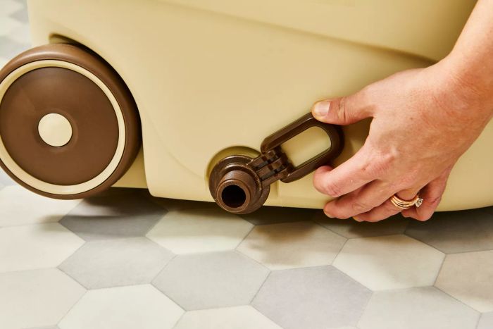 A hand adjusts the drainage system of the Oshang Spin Mop and Bucket on tile flooring.