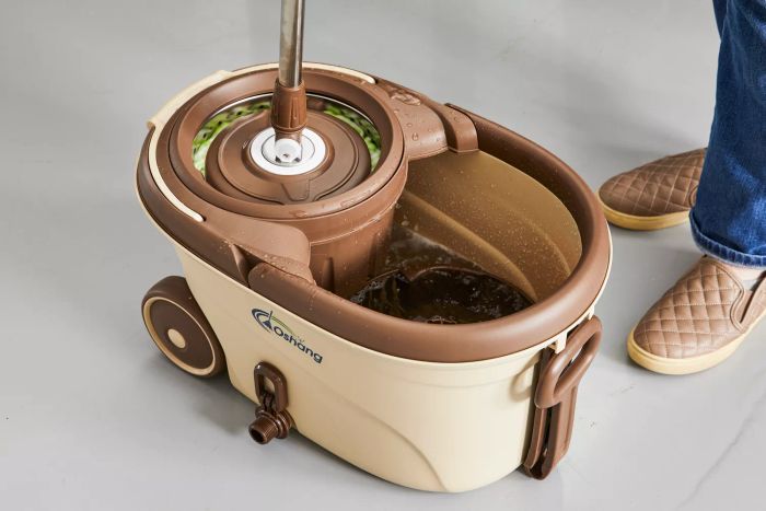 A person activates the spinning function on the Oshang Spin Mop and Bucket.