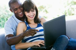 A couple laughing while holding a laptop