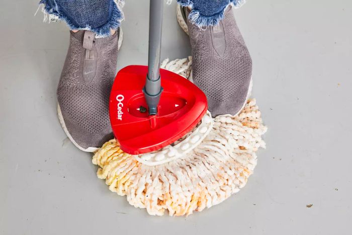 A person stands on the mop of the O-Cedar EasyWring Spin Mop and Bucket System