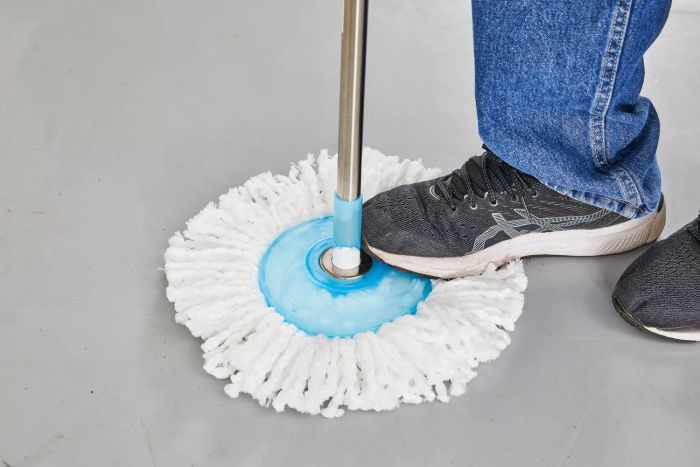 A person steps on the mop head of the Hurricane Spin Mop to activate the spinning mechanism.
