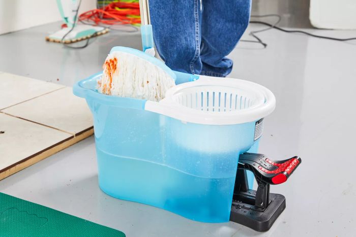A person dips the mop head of the Hurricane Spin Mop into water to begin cleaning.