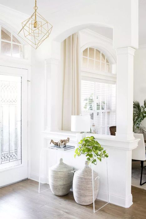 Sunny entryway featuring a lucite console table and a plant