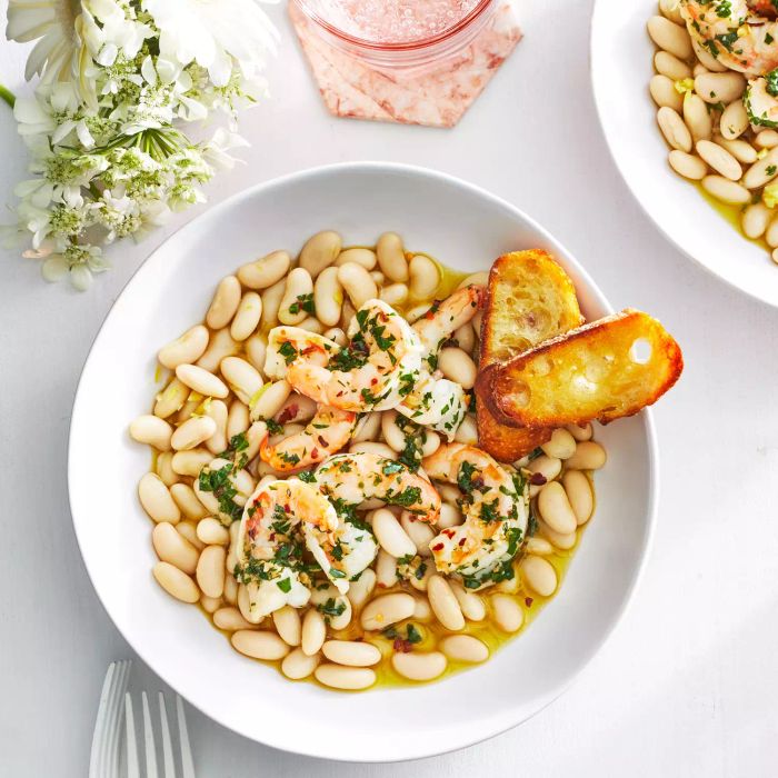An overhead shot of Buttery Shrimp served with marinated white beans in a white bowl.