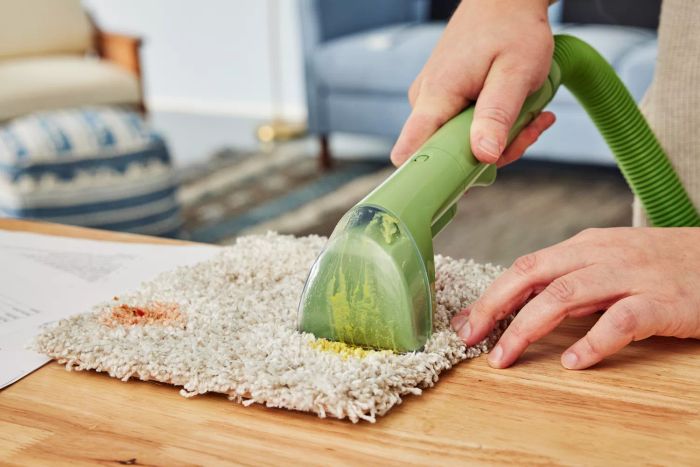 Hand cleaning a stained carpet square with the Bissell 1400B Little Green Multi-Purpose Portable Carpet and Upholstery Cleaner