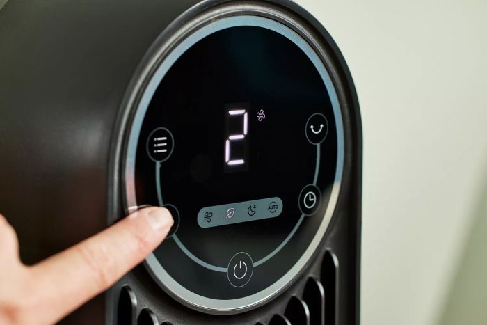 Finger pressing a button on the Dreo Nomad One Tower Fan