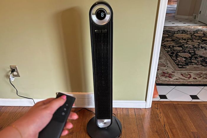 A person uses the remote control to adjust the settings on the DREO The Cruiser Pro T2 42-Inch Fan