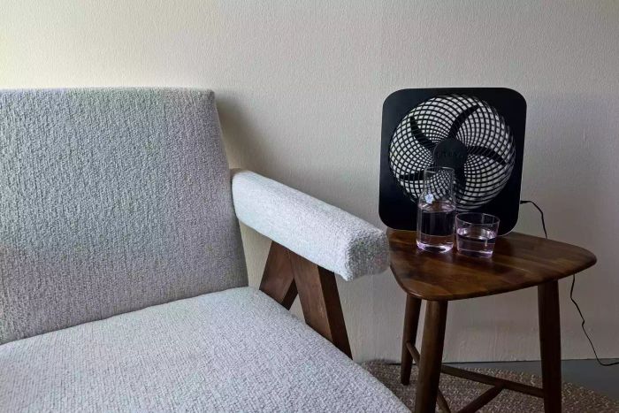 The Treva 10-Inch Portable Fan placed on a compact side table.