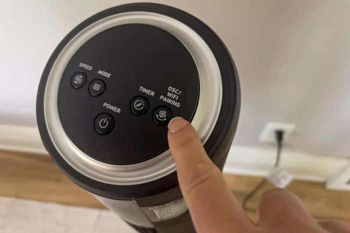 A person presses the WiFi pairing button on the top of the HOLMES 42 Inch SmartConnect WI-FI Digital Tower Fan