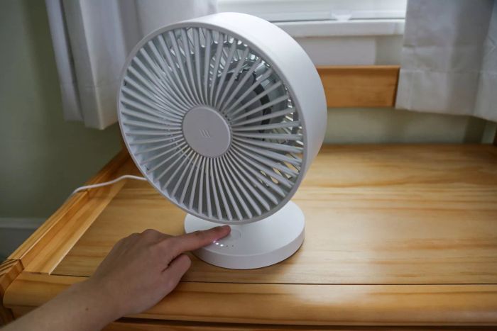 A person presses the power button on the Windmill Air Circulator & Fan