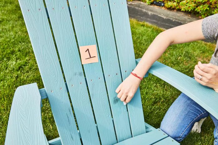 A woman is seen scrubbing away stains from the Yefu Plastic Adirondack Chair outside.