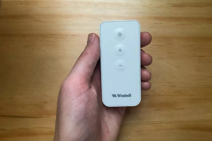 A person holds the remote control for the Windmill Air Circulator & Fan