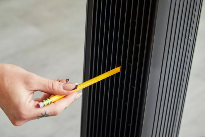 Hand placing a pencil into the Dreo Nomad One Tower Fan
