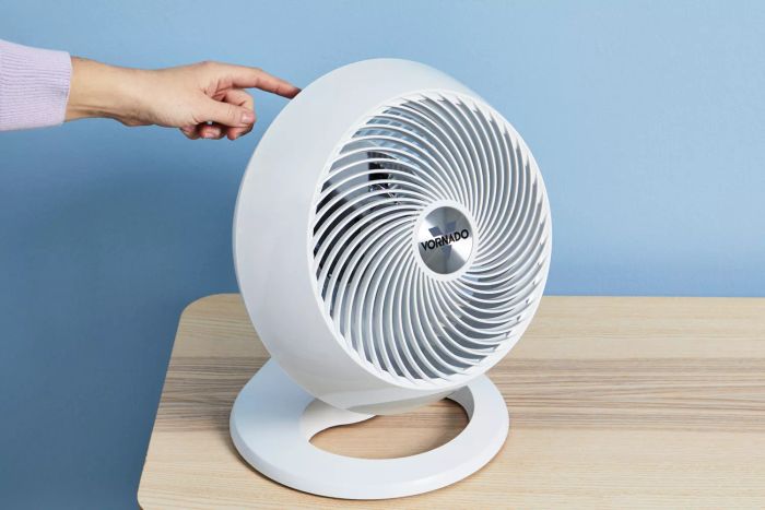Hand adjusting the Vornado 660 Large Air Circulator on an oak wood desk