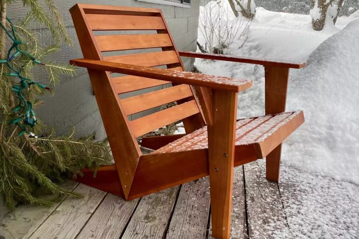 The Joss & Main Ursa Acacia Outdoor Adirondack Chair dusted with snow, standing gracefully in the winter landscape.