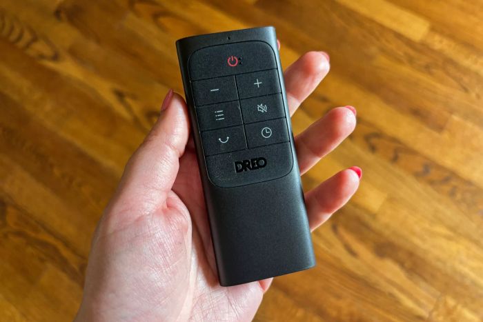 A person holds the remote control in front of the DREO The Cruiser Pro T2 42-Inch Fan