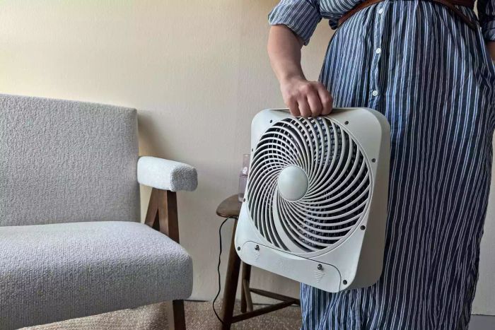 A person showing the back of the Treva 10-Inch Portable Fan.