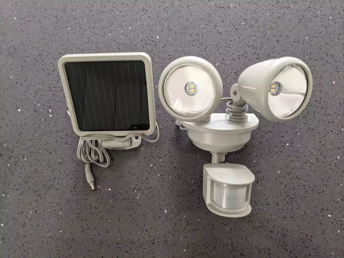Parts of the Maxsa Motion-Activated Dual Head Solar Security Light arranged on a grey surface