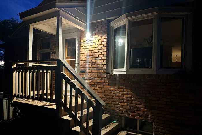 Euri Lighting EFL-130W-MD Flickering Flame Lantern glowing on the exterior wall of a home during the night