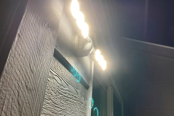 The SANSI 45W Motion Sensor Outdoor Floodlight shining brightly at night on the side of a house