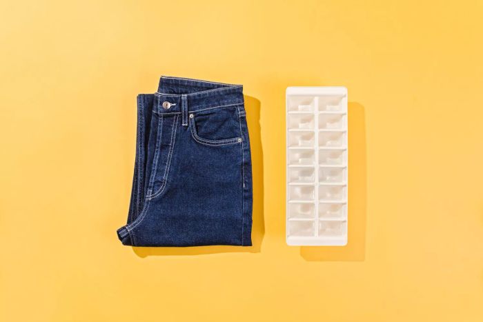 A pair of high-end jeans neatly folded into a square, accompanied by a tray of ice cubes