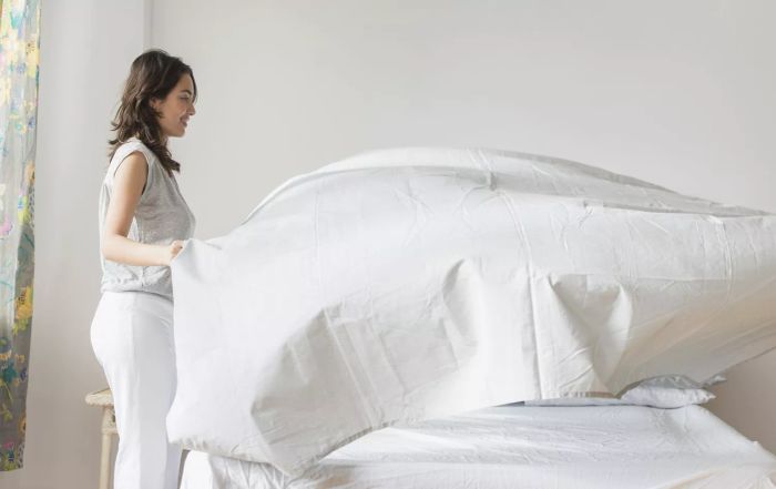 Image: Woman putting white sheets on a bed