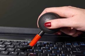 A woman using a specialized brush to clean a computer keyboard.