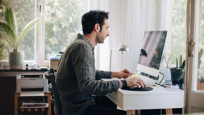 A person working on a computer at their home office desk.