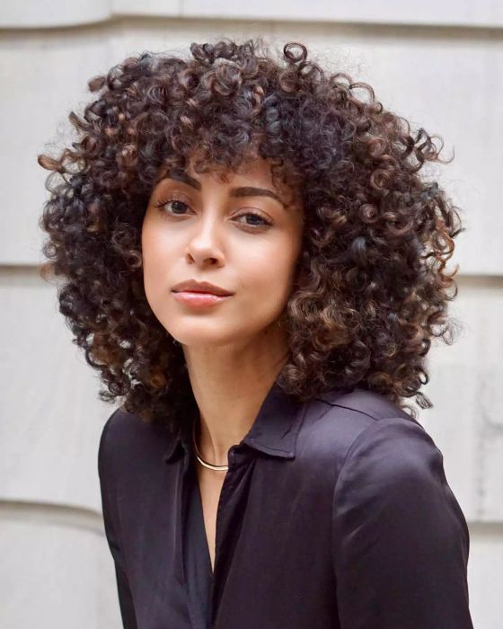 Halo hairstyle on a model with natural curls, wearing a black button-up blouse