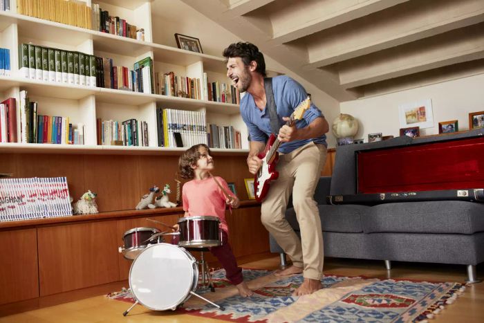 Dad strumming guitar with his son by his side