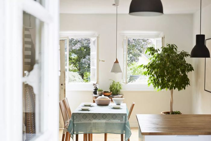 A bright, modern kitchen and dining area in a vintage country home with no window coverings