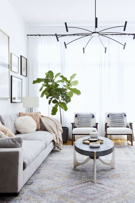 Living Room with light gray couch, 2 white chairs and white coffee table, corner green plant, and sheer white curtains