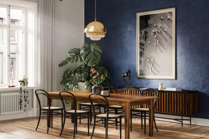 A chic dining space in a contemporary home featuring a wooden table with six chairs, a hanging electric light fixture, and a large framed photo against a striking blue wall.