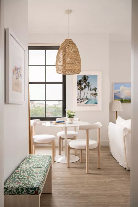 A white dining area featuring pendant lighting, art pieces, and a table with chairs.