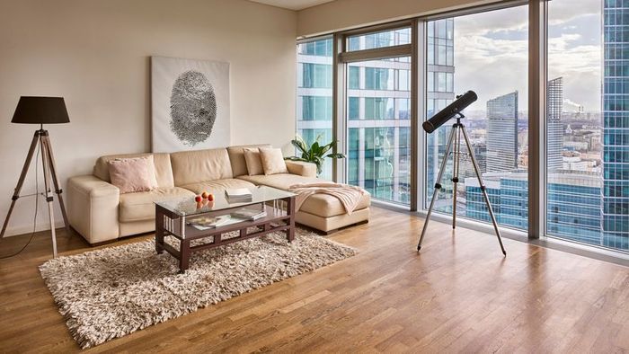 A telescope positioned to observe through an apartment’s glass window.