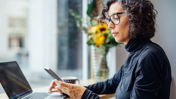 A woman using both her laptop and phone