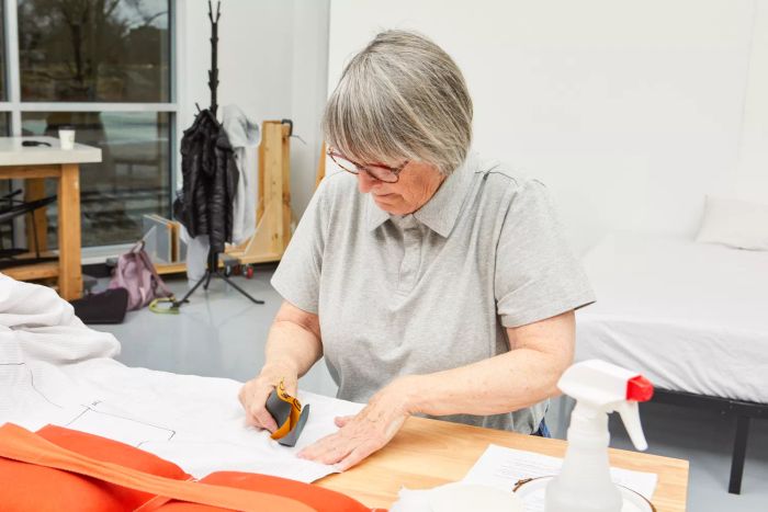 A person applying sandpaper to The Citizenry Organic Resort Cotton Sheet Set placed on a table.