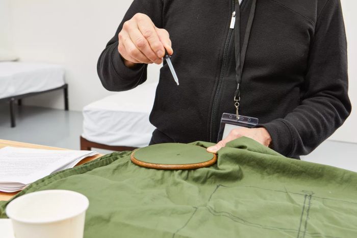 A person using a dropper to spill liquid onto the Nest Bedding Sateen Organic Cotton Sheet Set.