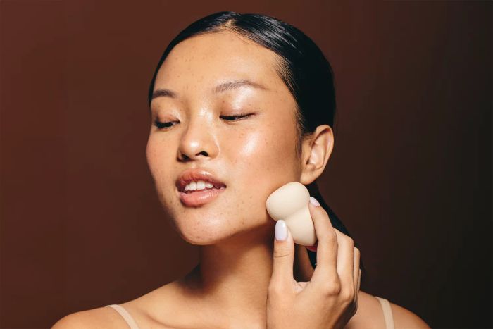 A woman applying bronzer to enhance her features