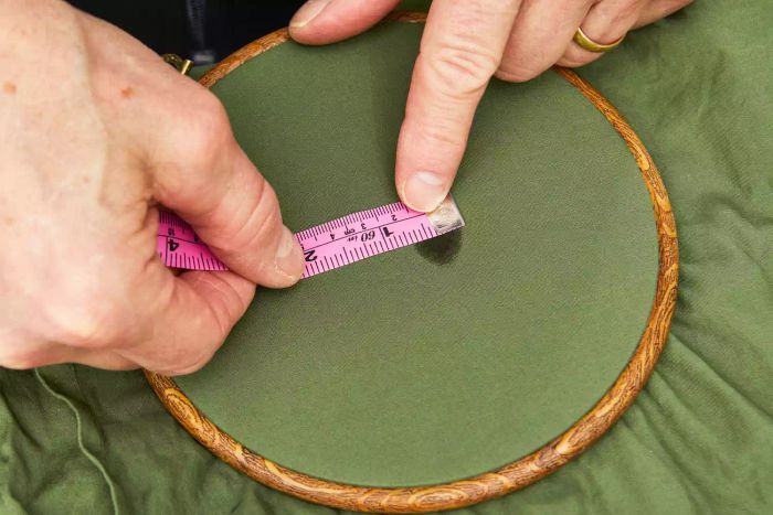 A person using a measuring tape to assess the size of a stain on the Nest Bedding Sateen Organic Cotton Sheet Set.