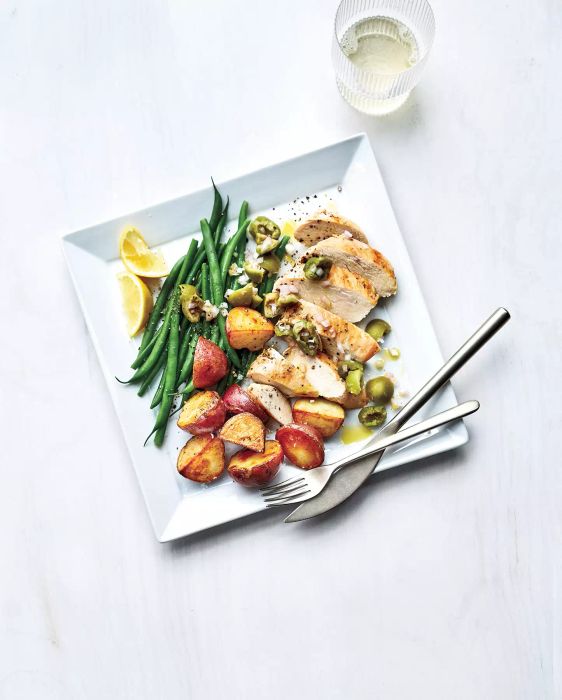 Sheet-Pan chicken with potatoes and green beans served on a white, square plate.