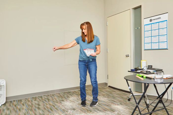 A person sprinkling powder onto a carpeted floor.
