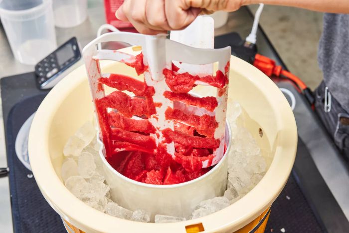 A person pulling the mixing attachment out of the Nostalgia 4-Quart Wood Bucket Ice Cream Maker