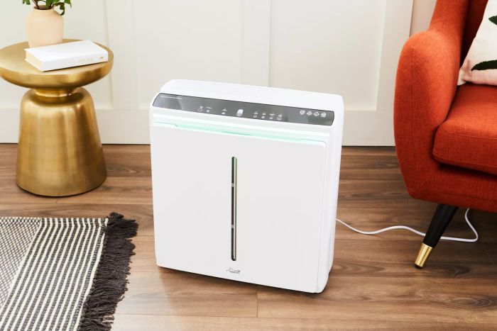 The Rabbit Air A3 Ultra Quiet HEPA Air Purifier placed on a wooden floor next to a chair.