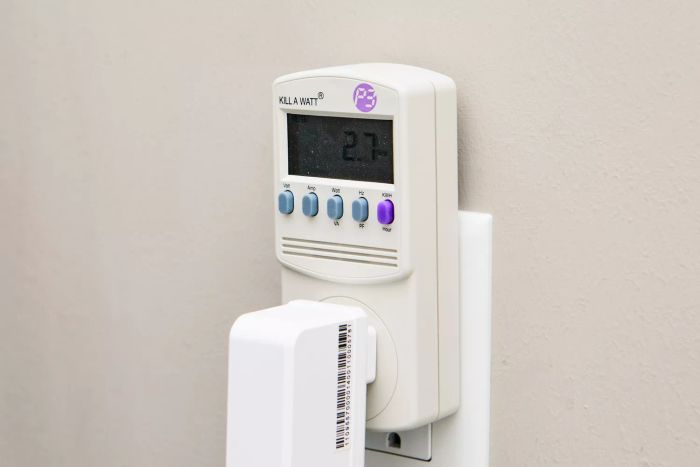 A Kill A Watt electricity usage monitor plugged into an electrical outlet.